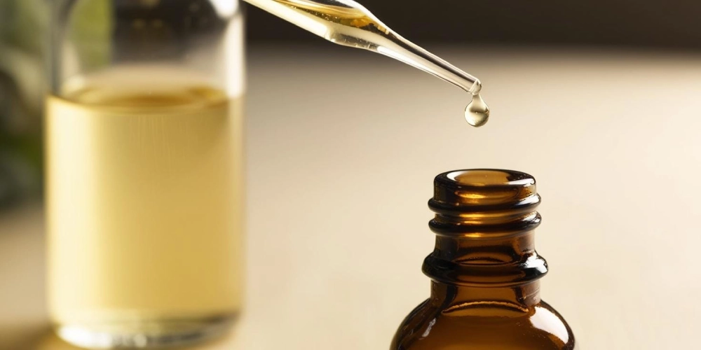 Close-up van een amberkleurig flesje met pipet waar een druppel lichtgele vloeistof uit valt, gebruikt voor paddo druppels